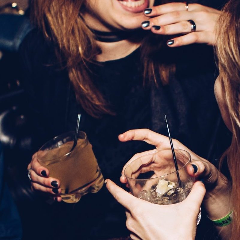 two women talking while holding drinking glasses